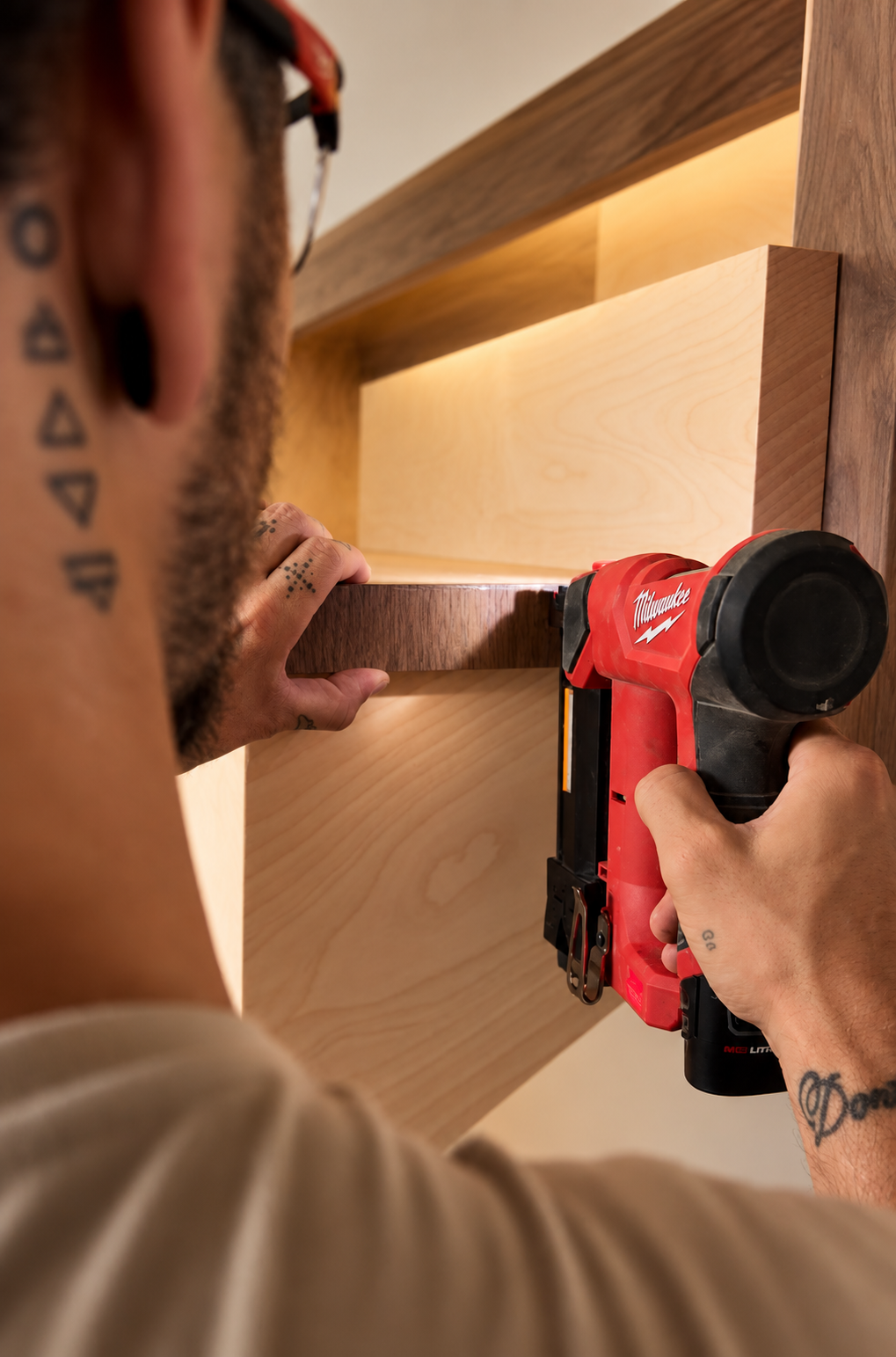 A craftsman using a nail gun to attach wood trim to a cabinet